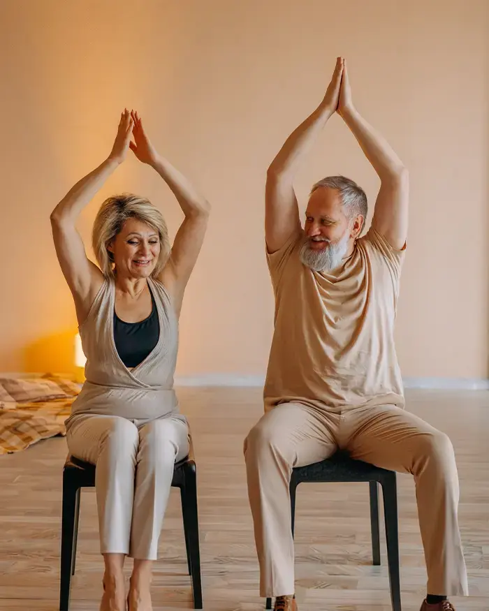 Deux personnes seniors pratiquant le yoga, bras levés